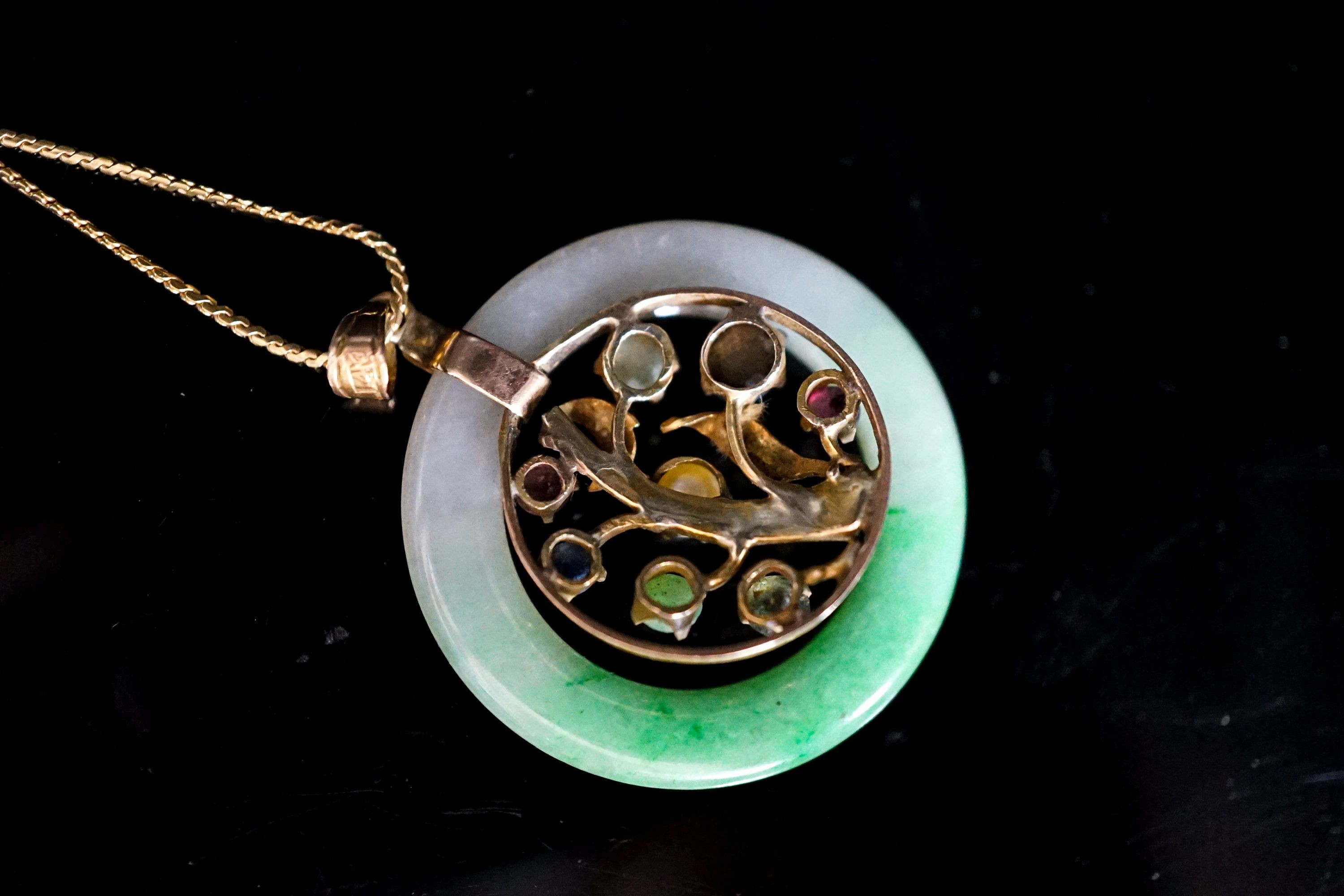 A yellow metal and gem set mounted jade disc pendant, 30mm on s yellow metal fine link chain, gross weight 9.2 grams.